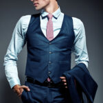 Young elegant handsome businessman male model in blue suit and fashionable glasses, posing in studio